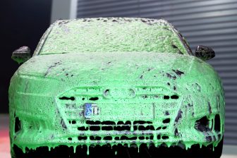 Auto ist mit grünem Schaum in der SB-Autowaschanlage bedeckt.