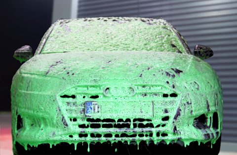 Auto ist mit grünem Schaum in der SB-Autowaschanlage bedeckt.